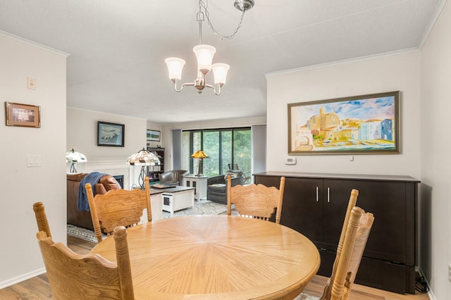 dining area featuring light hardwood / wood-style floors, ornamental molding, and an inviting chandelier