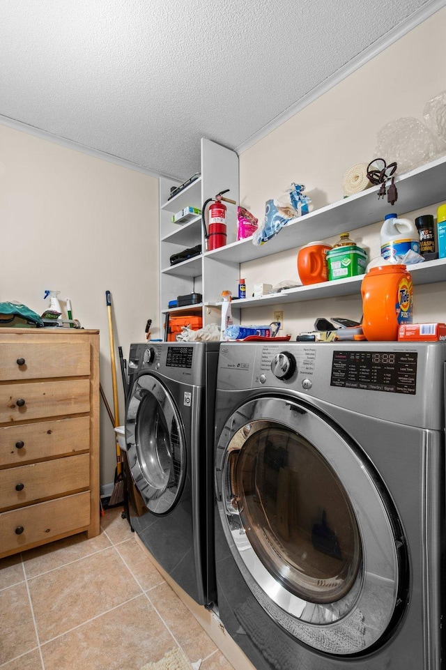 laundry area with light tile patterned floors, a textured ceiling, and washing machine and clothes dryer