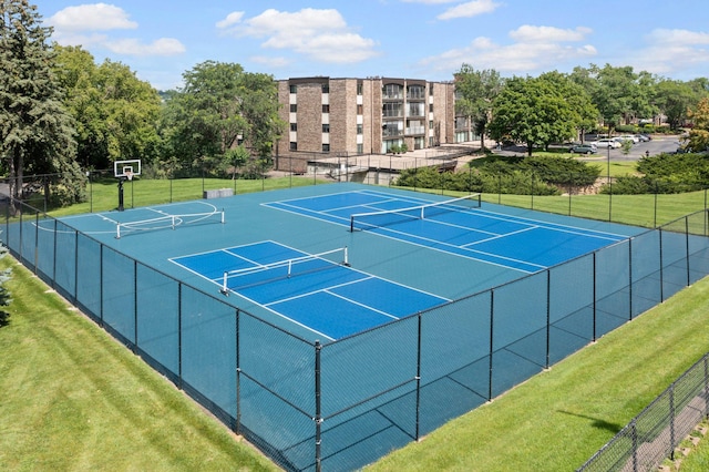 view of tennis court featuring basketball hoop and a lawn