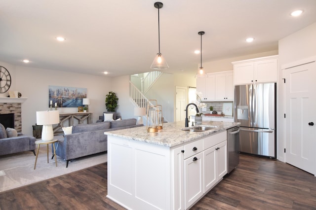 kitchen featuring dark wood-type flooring, stainless steel appliances, white cabinetry, and a center island with sink