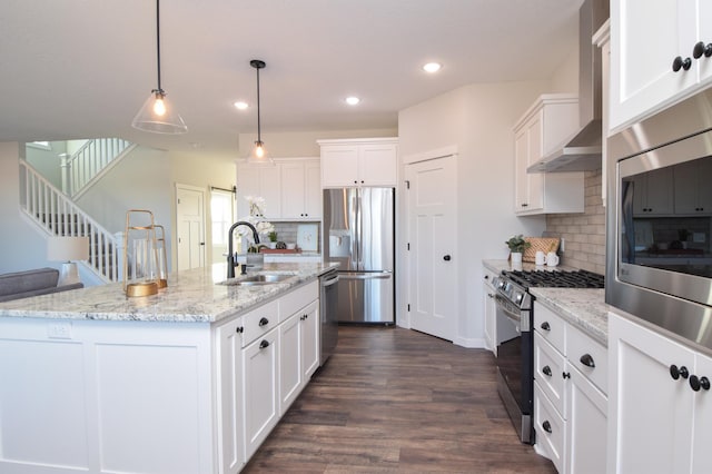 kitchen with white cabinets, sink, wall chimney exhaust hood, an island with sink, and stainless steel appliances