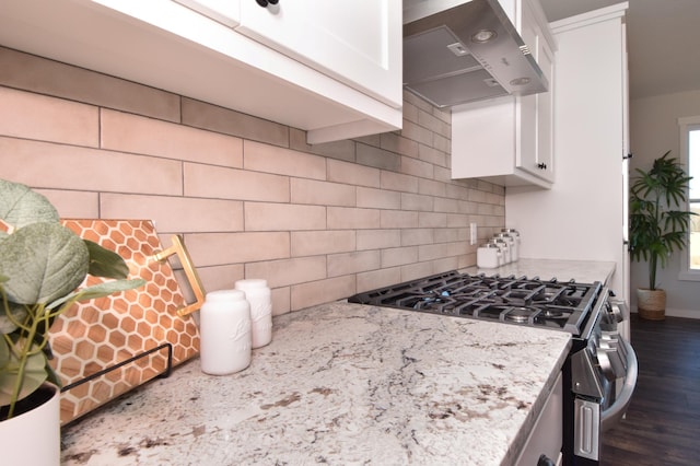 kitchen featuring dark hardwood / wood-style flooring, white cabinetry, stainless steel gas stove, and wall chimney range hood