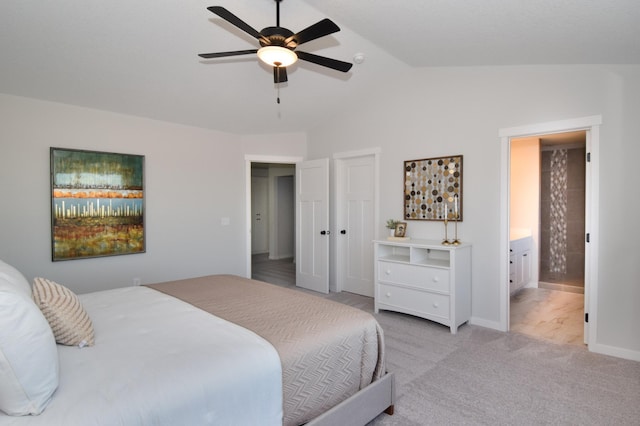 bedroom featuring ceiling fan, light colored carpet, ensuite bathroom, and vaulted ceiling