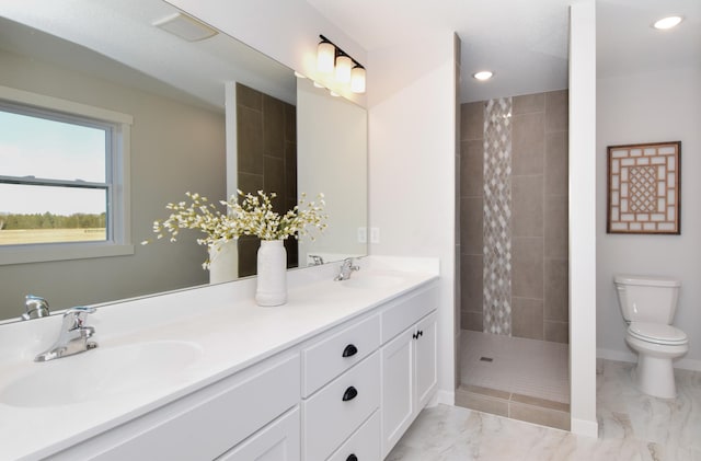 bathroom featuring a tile shower, vanity, and toilet