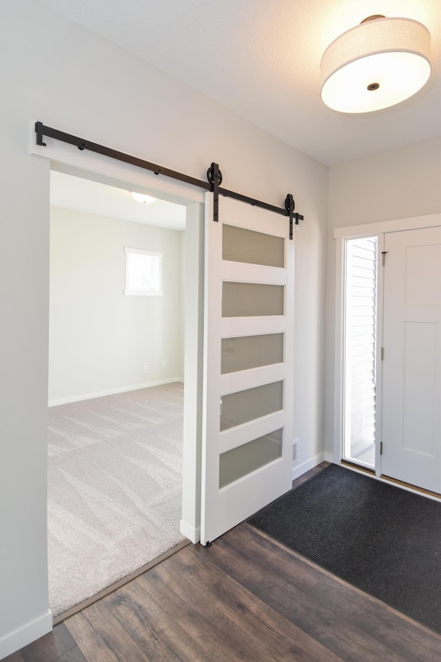 entryway with a barn door and dark wood-type flooring