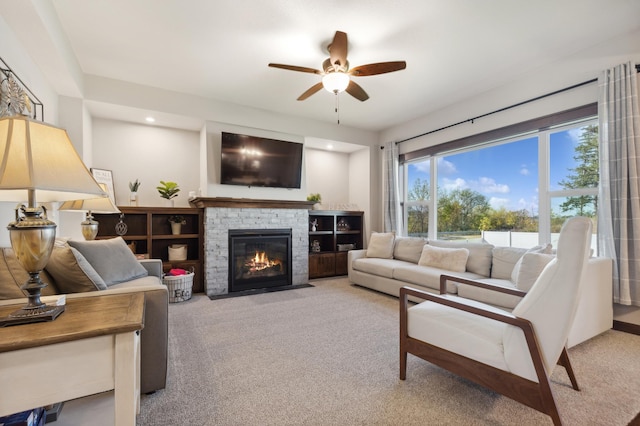 living room featuring ceiling fan, light colored carpet, and a fireplace