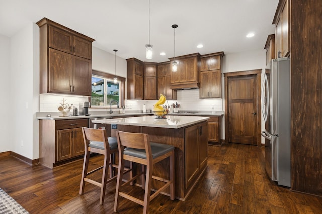 kitchen with pendant lighting, a center island, dark hardwood / wood-style floors, and stainless steel refrigerator