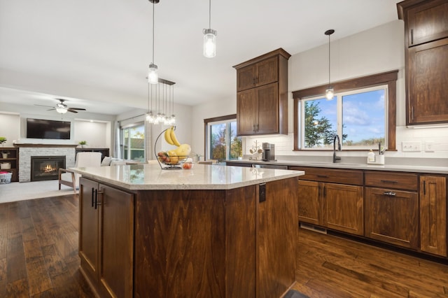 kitchen with dark hardwood / wood-style floors, a stone fireplace, and a healthy amount of sunlight