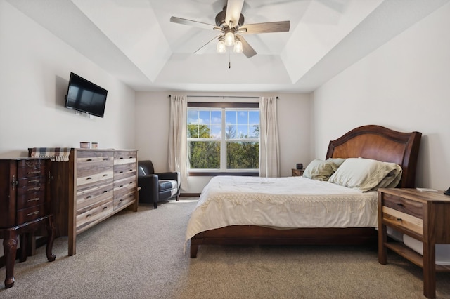 carpeted bedroom with a tray ceiling and ceiling fan