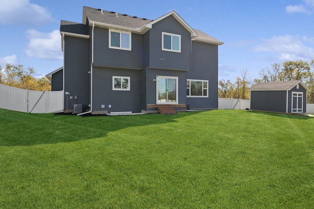 back of house with central air condition unit, a yard, and a storage shed