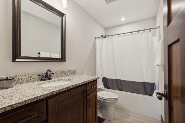 full bathroom featuring hardwood / wood-style floors, toilet, shower / bathtub combination with curtain, and vanity