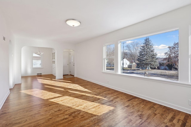 empty room featuring a chandelier, hardwood / wood-style floors, and a healthy amount of sunlight