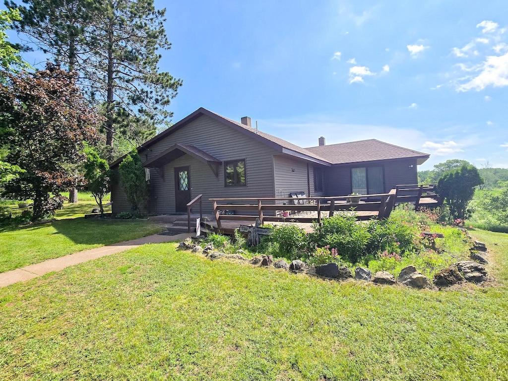 back of property with a wooden deck and a yard