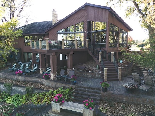 1516 Bay Oaks Dr, Albert Lea, MN 56007 - back of property featuring stairs, a patio area, a sunroom, a chimney, and a shingled roof