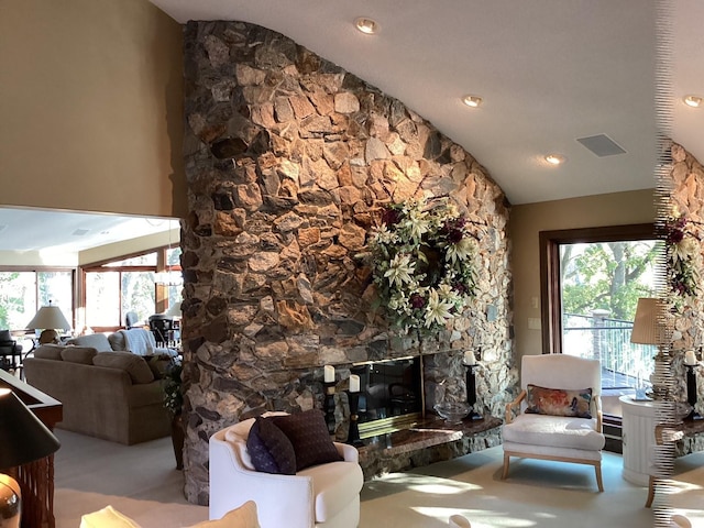 living room with a stone fireplace and lofted ceiling