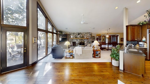 1516 Bay Oaks Dr, Albert Lea, MN 56007 - living room featuring a ceiling fan, high vaulted ceiling, wood-type flooring, and a stone fireplace