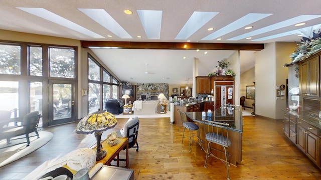 interior space featuring a skylight, high vaulted ceiling, and light hardwood / wood-style floors