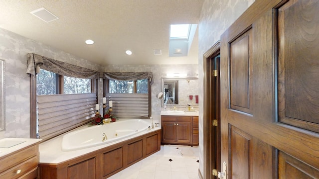 bathroom with vanity, a skylight, tile patterned flooring, a textured ceiling, and a tub