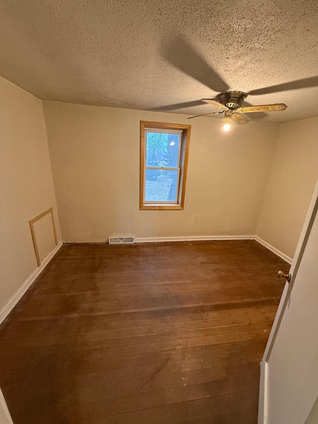 unfurnished room with a textured ceiling, ceiling fan, and dark wood-type flooring