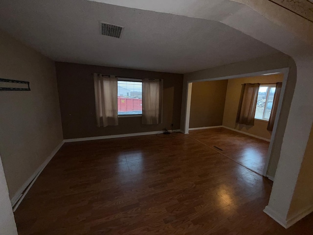 unfurnished room featuring dark hardwood / wood-style flooring, plenty of natural light, and lofted ceiling