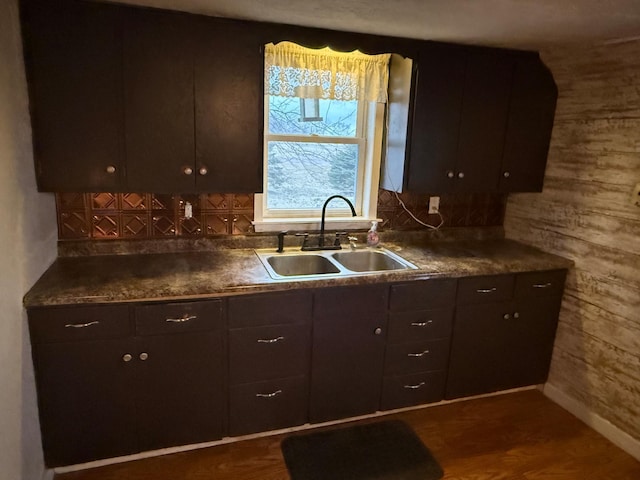 kitchen with dark brown cabinetry, wood walls, sink, and dark hardwood / wood-style flooring