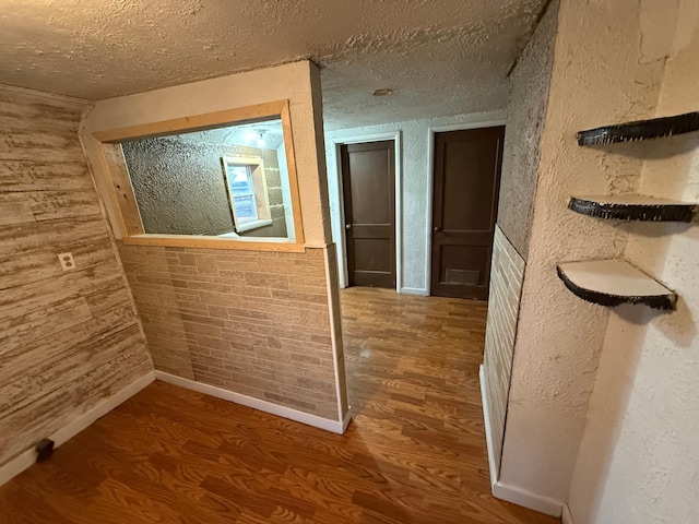 corridor with a textured ceiling and hardwood / wood-style flooring