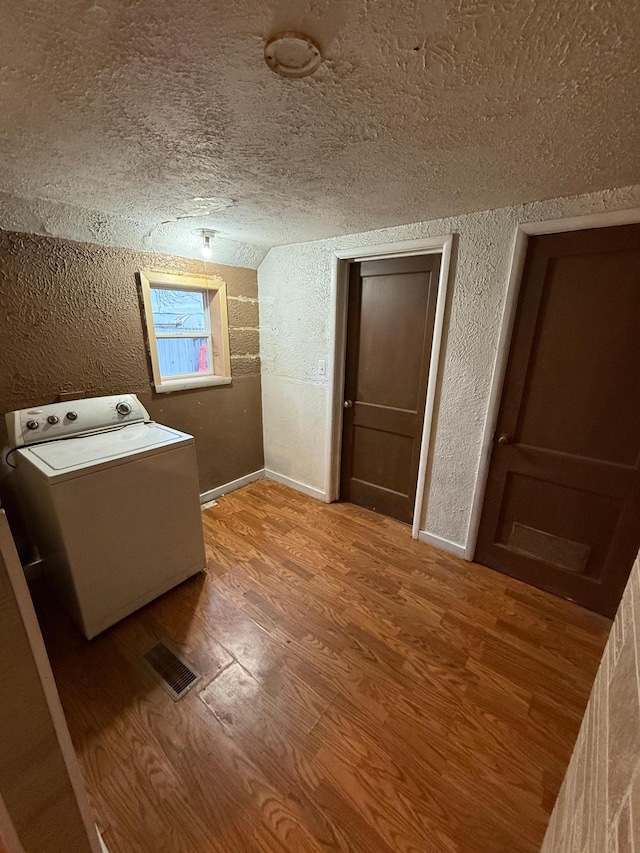 bathroom with washer / clothes dryer, a textured ceiling, and hardwood / wood-style flooring