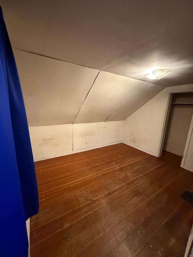 bonus room with dark wood-type flooring and vaulted ceiling