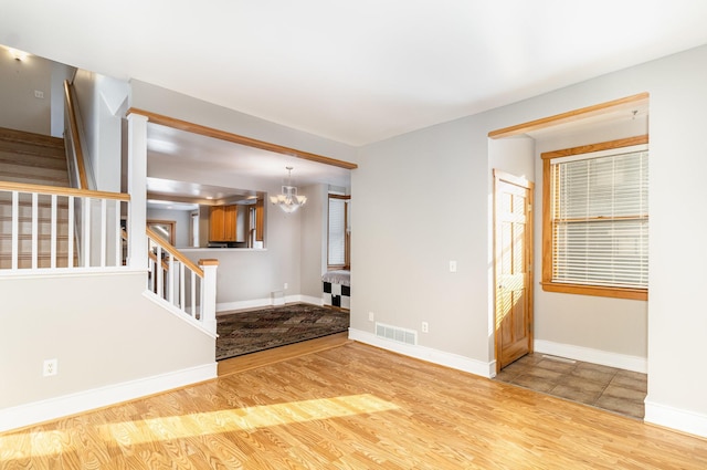 empty room with light hardwood / wood-style floors and an inviting chandelier