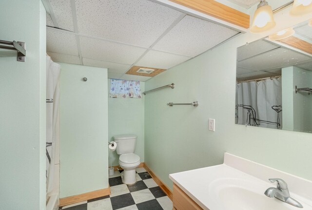 bathroom with vanity, a paneled ceiling, toilet, and curtained shower