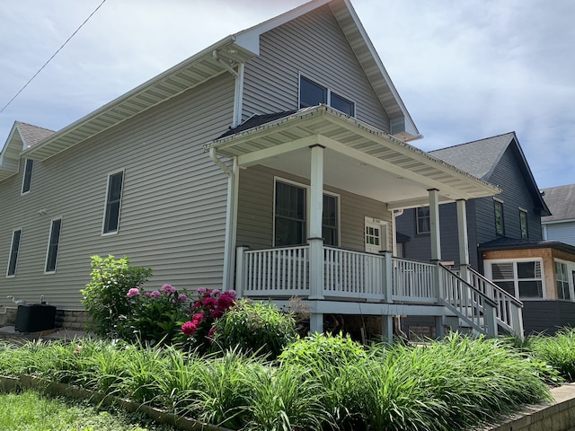 back of property with covered porch and central AC