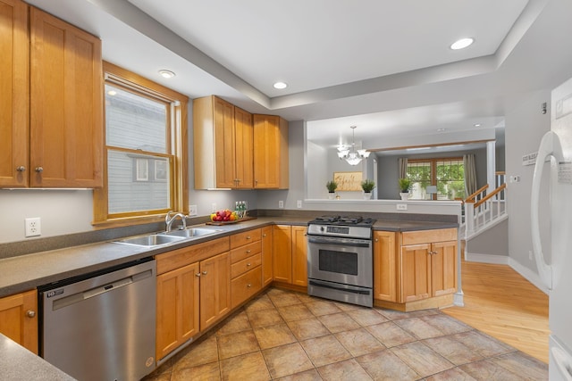 1096 14th Ave SE, Minneapolis, MN 55414 - kitchen featuring appliances with stainless steel finishes, a raised ceiling, a peninsula, a chandelier, and dark countertops