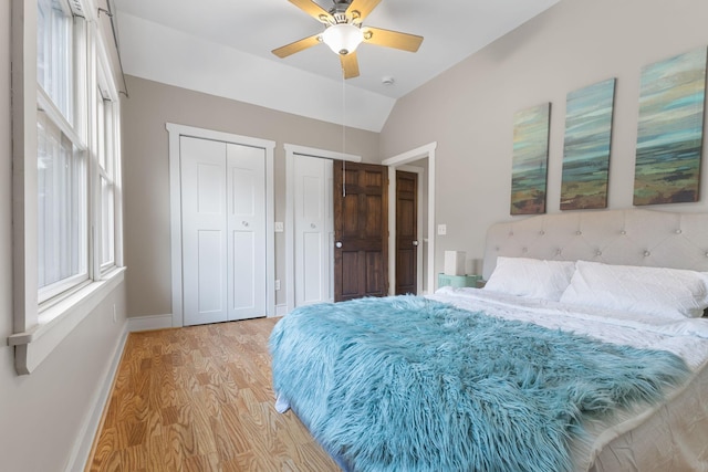 1096 14th Ave SE, Minneapolis, MN 55414 - bedroom with multiple closets, light wood-style flooring, multiple windows, vaulted ceiling, and a ceiling fan