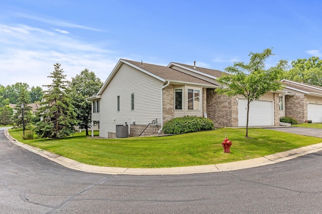 view of front of property featuring a garage, a front lawn, and central air condition unit