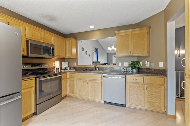 kitchen featuring sink, a textured ceiling, appliances with stainless steel finishes, light hardwood / wood-style floors, and a chandelier