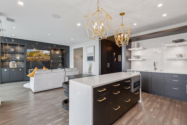 kitchen with sink, decorative light fixtures, hardwood / wood-style flooring, a center island, and stainless steel microwave