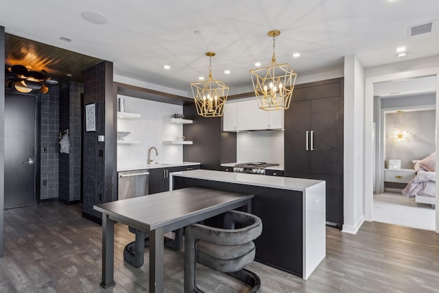 kitchen featuring a center island, white cabinets, sink, stainless steel dishwasher, and decorative light fixtures