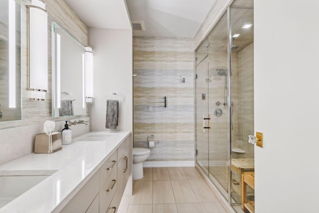 bathroom featuring tile patterned floors, vanity, tile walls, toilet, and a shower with shower door