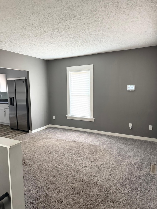 empty room featuring carpet and a textured ceiling