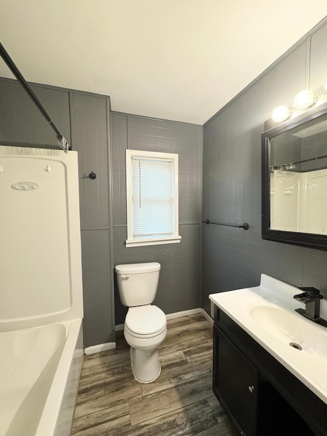 full bathroom with hardwood / wood-style floors, vanity, toilet, and tile walls