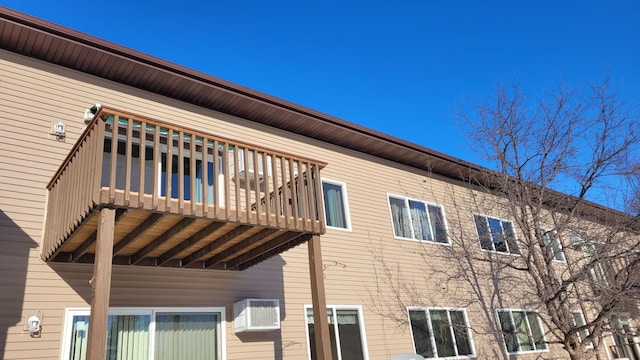 view of side of home with a wall mounted air conditioner and a balcony