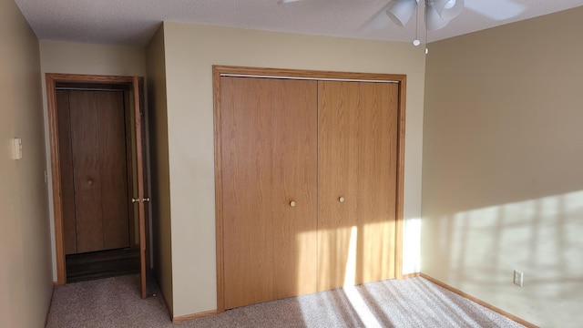 unfurnished bedroom featuring a textured ceiling, ceiling fan, light carpet, and a closet