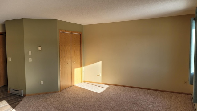 carpeted spare room featuring a textured ceiling and a baseboard heating unit