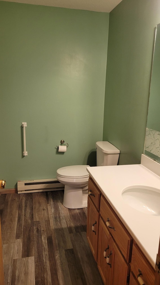 bathroom with toilet, vanity, a baseboard radiator, and wood-type flooring