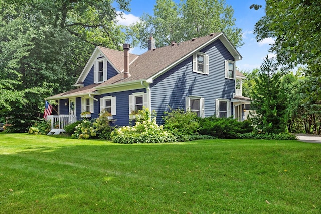 view of side of home featuring a shingled roof and a yard