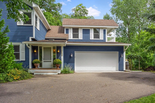 view of front of property with driveway, roof with shingles, and an attached garage
