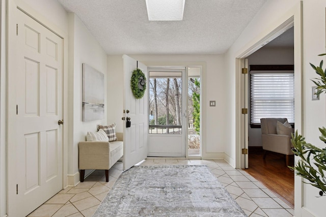 foyer entrance with light tile patterned floors, baseboards, and a textured ceiling