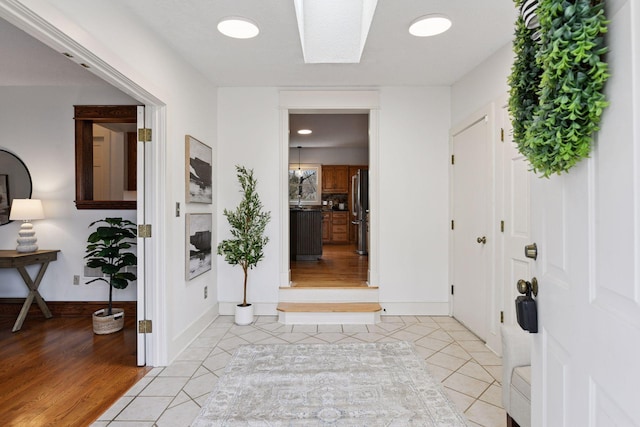 entrance foyer with baseboards, a skylight, and light tile patterned floors