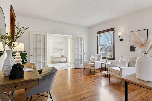 office area with french doors, light wood-style flooring, and a textured ceiling