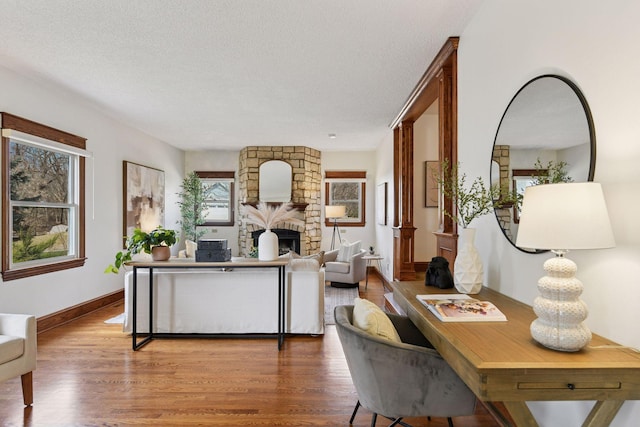 living area featuring a textured ceiling, a fireplace, and wood finished floors